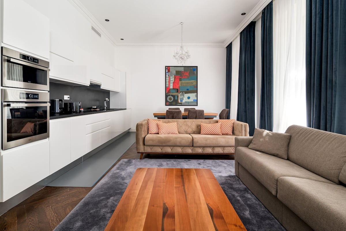 A modern kitchen with built-in appliances, a dining area with a sofa and table, and a large painting on the wall.