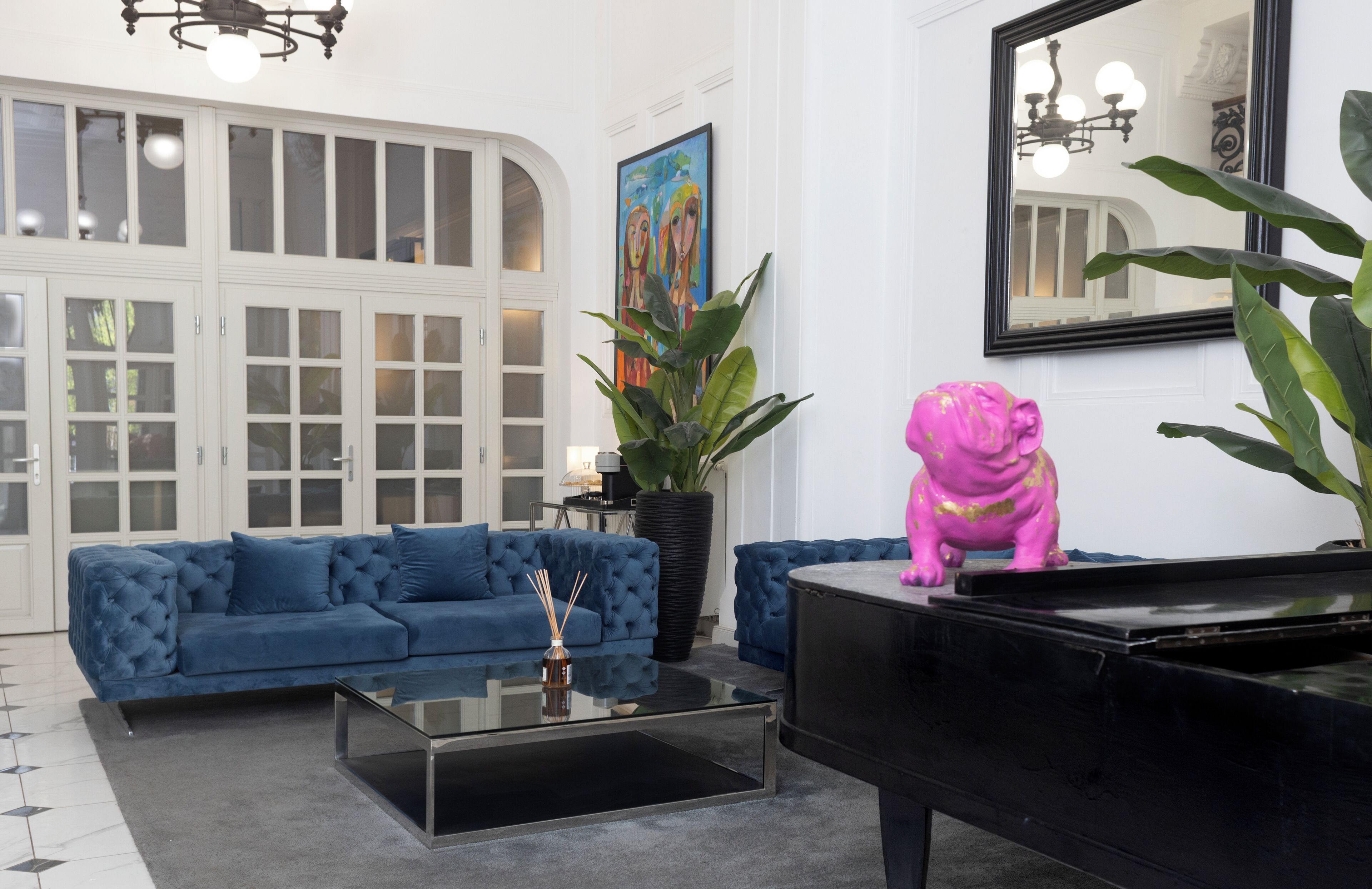 A modern living room with a blue sofa, a black piano, and a large potted plant.