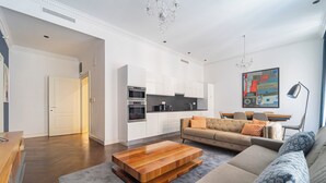 A modern living room with a sofa, coffee table, and a dining area with chairs. - ZOYA LUXURY RESIDENCE (Budapest)