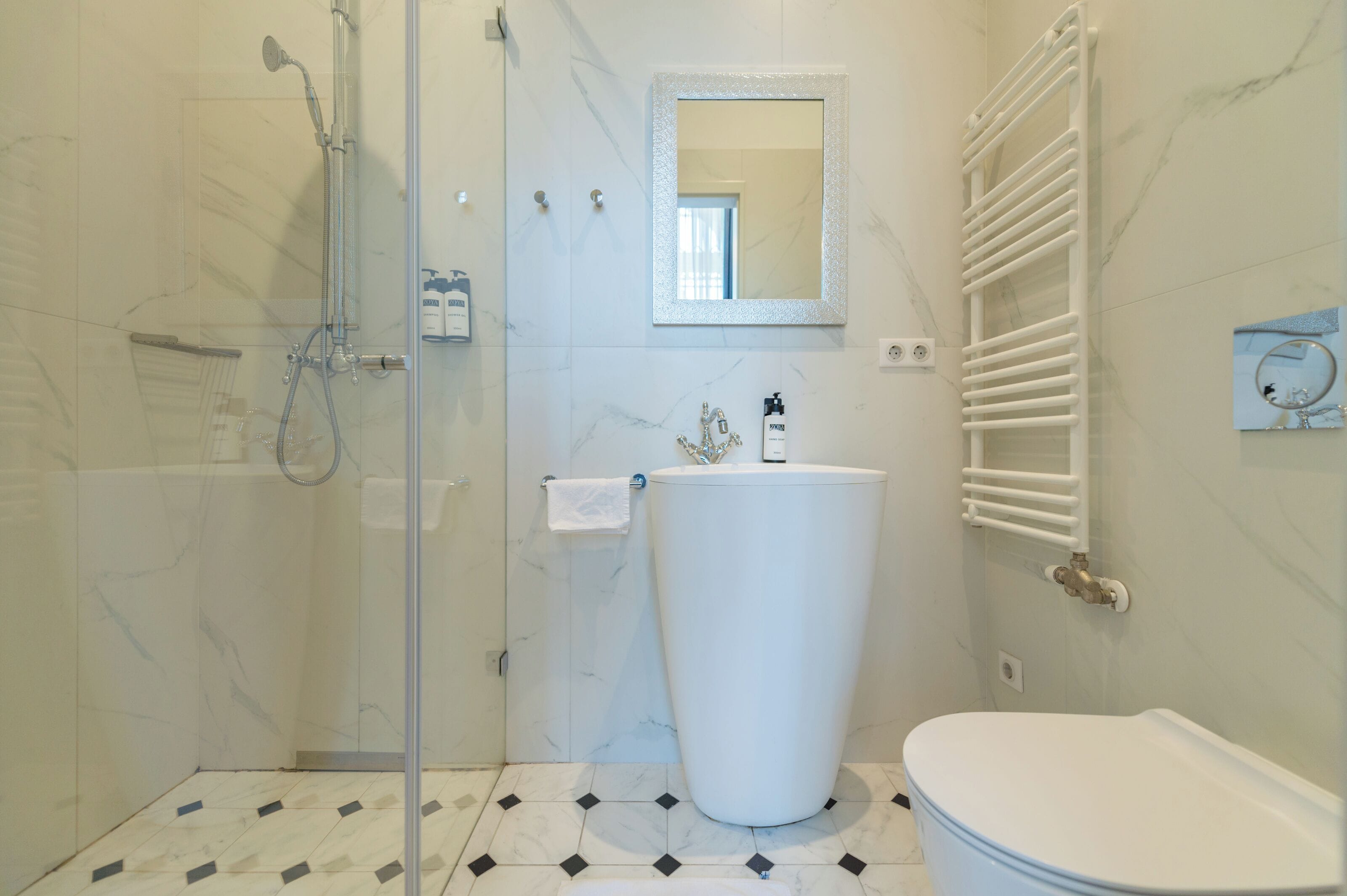 Un bagno moderno con doccia vetrata, lavandino bianco e water.