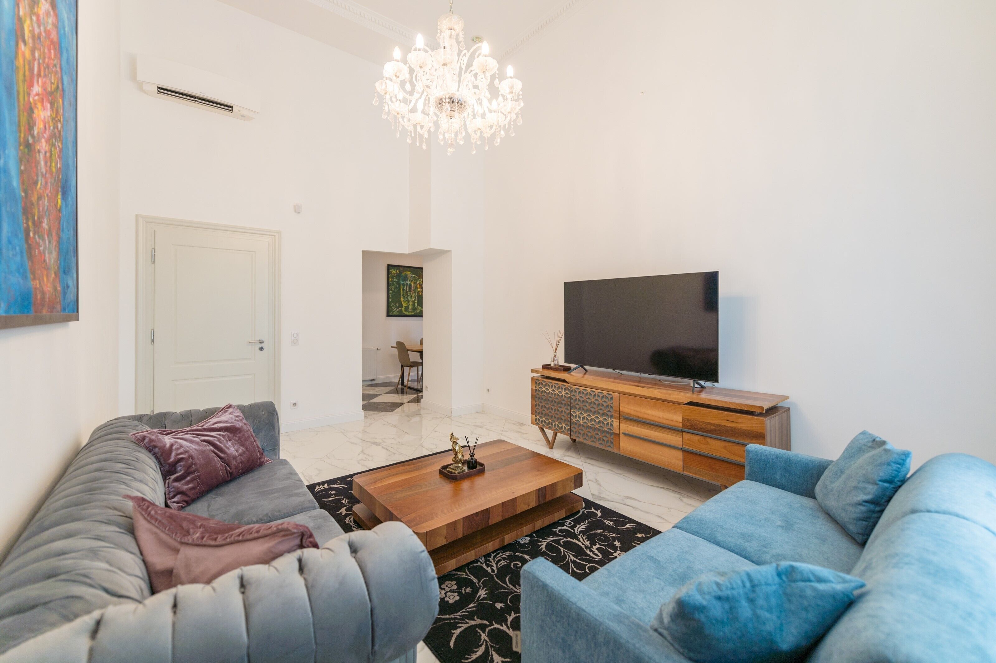 A modern living room with a large TV, a wooden cabinet, and two sofas.