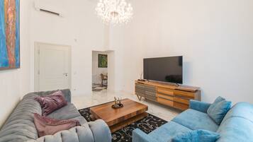 A modern living room with a large TV, a wooden cabinet, and two sofas.