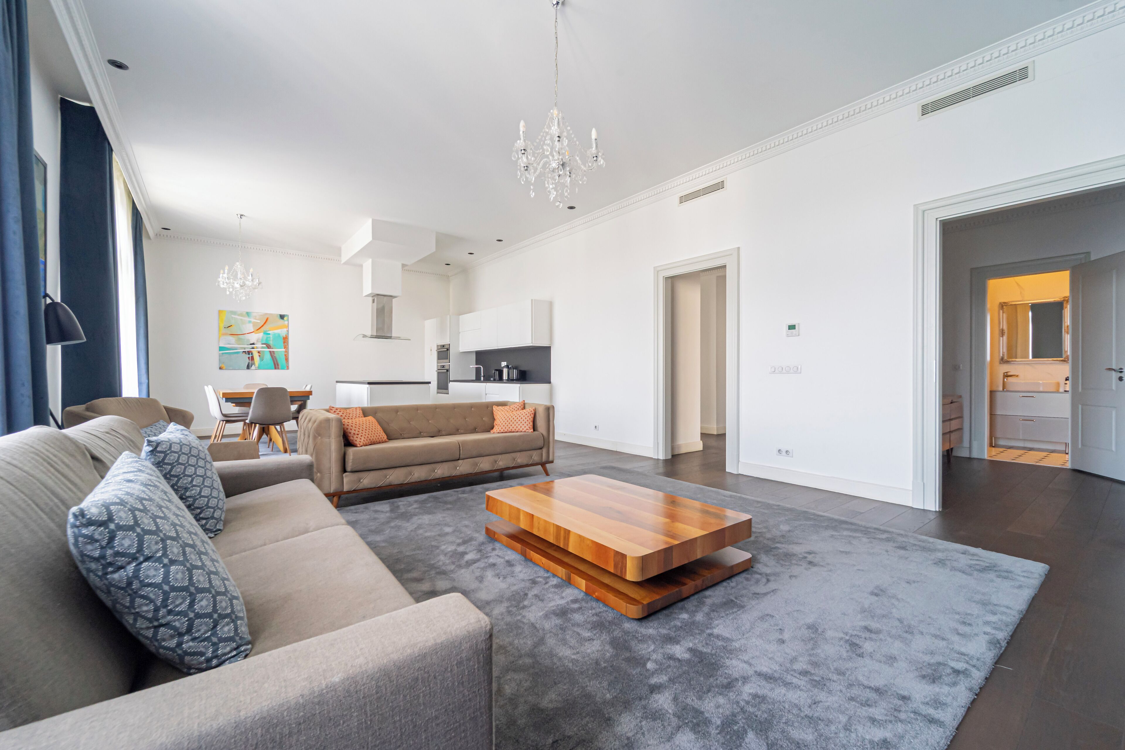 A modern living room with a sofa, coffee table, and a chandelier.