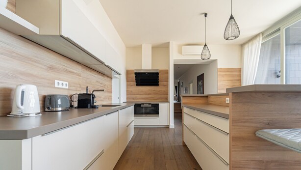 A modern kitchen with wooden flooring, white cabinetry, and a built-in oven. - ZOYA LUXURY RESIDENCE (Budapest)