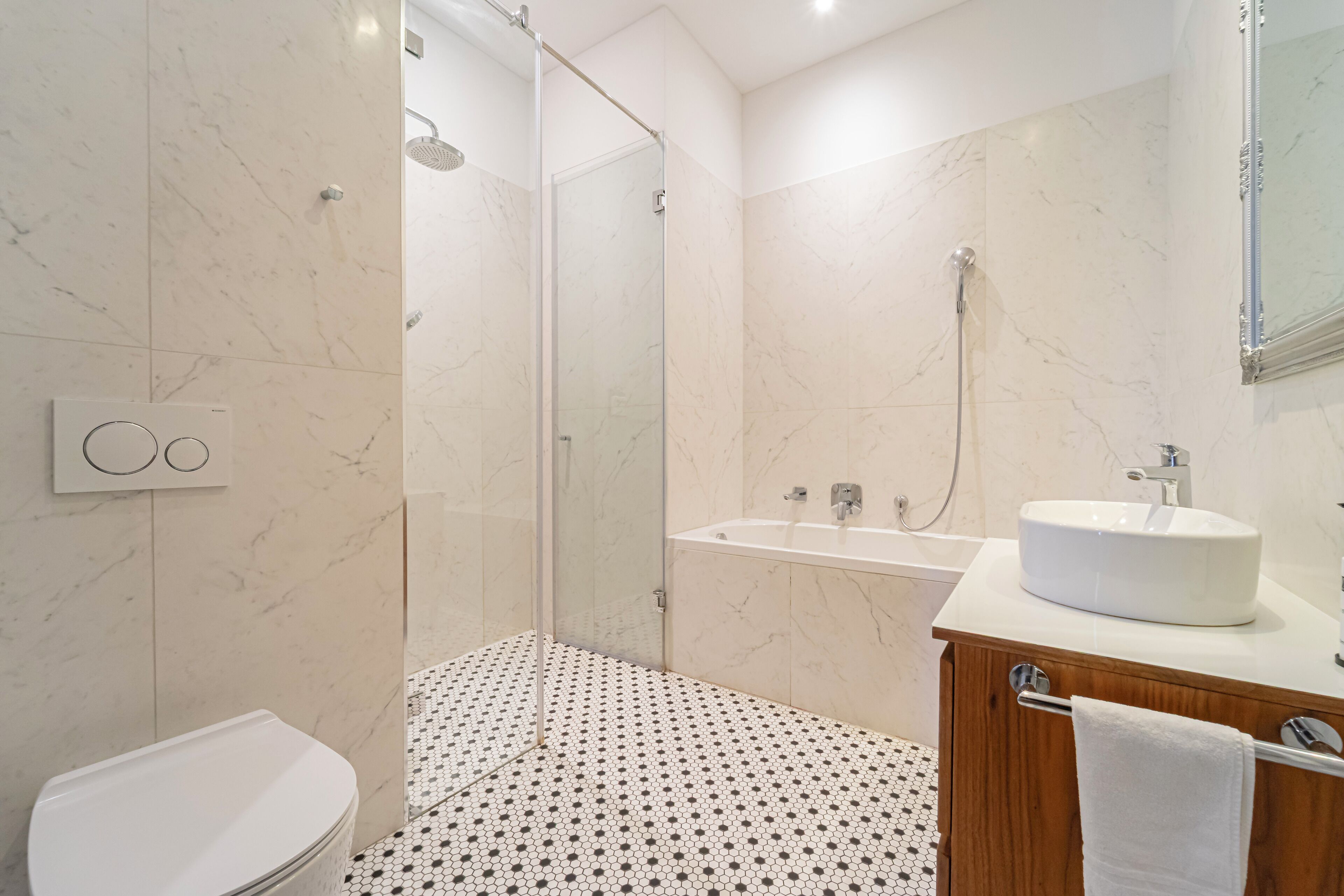 A modern bathroom with a glass-enclosed shower, a white sink, and a wooden vanity.