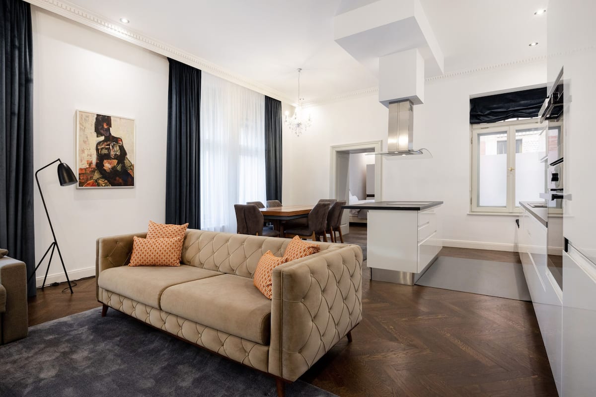 A modern living room with a beige sofa, a dining area, and a kitchen.