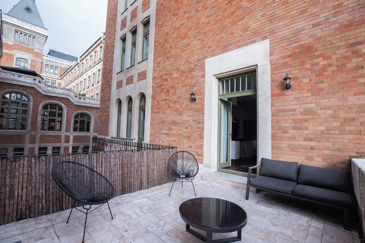 A patio with a round table, two chairs, and a sofa.