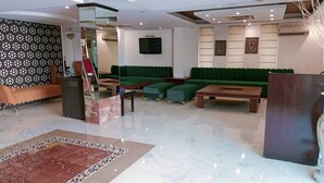 A modern lobby with green seating, a marble floor, and a glass partition. - Surasena Regalvista (Agra)