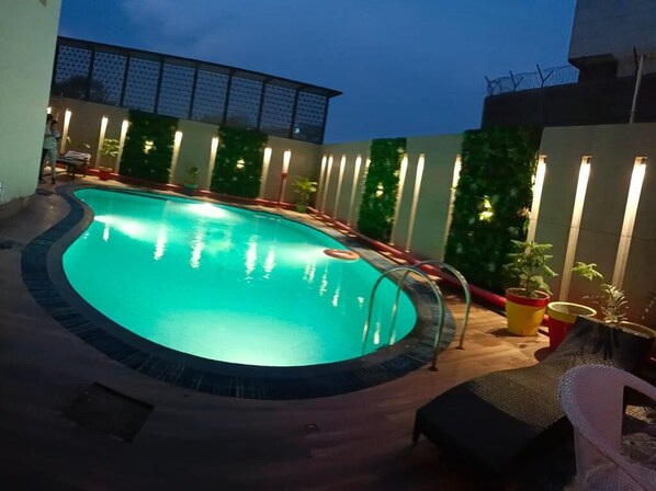 A circular swimming pool with a tiled edge, surrounded by a wooden deck and potted plants. - Surasena Regalvista (Agra)