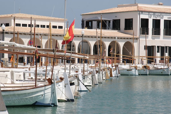 A marina with multiple boats docked, a building with arches, and a flag.
