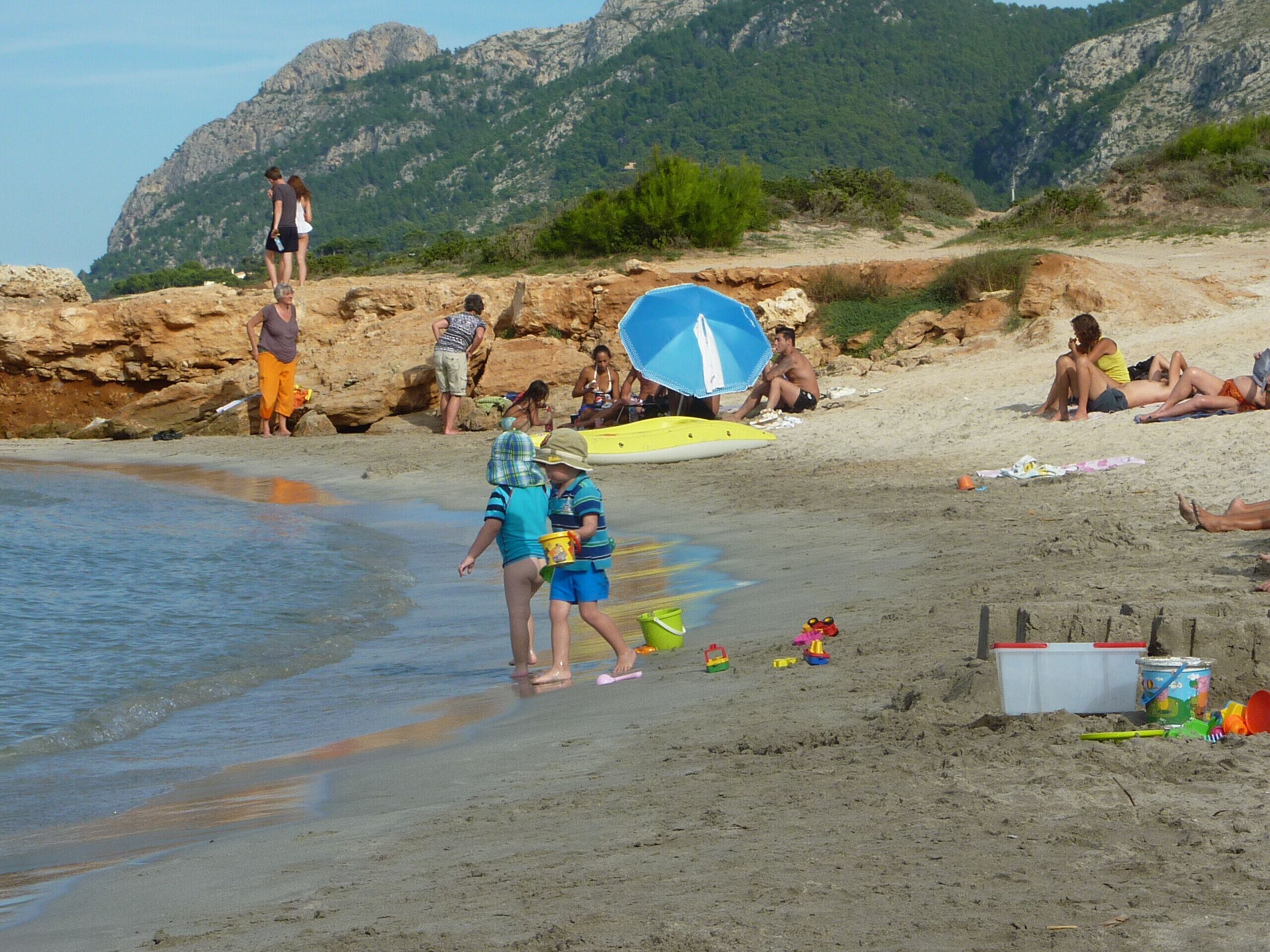 Een strand met mensen die ontspannen en kinderen die spelen.