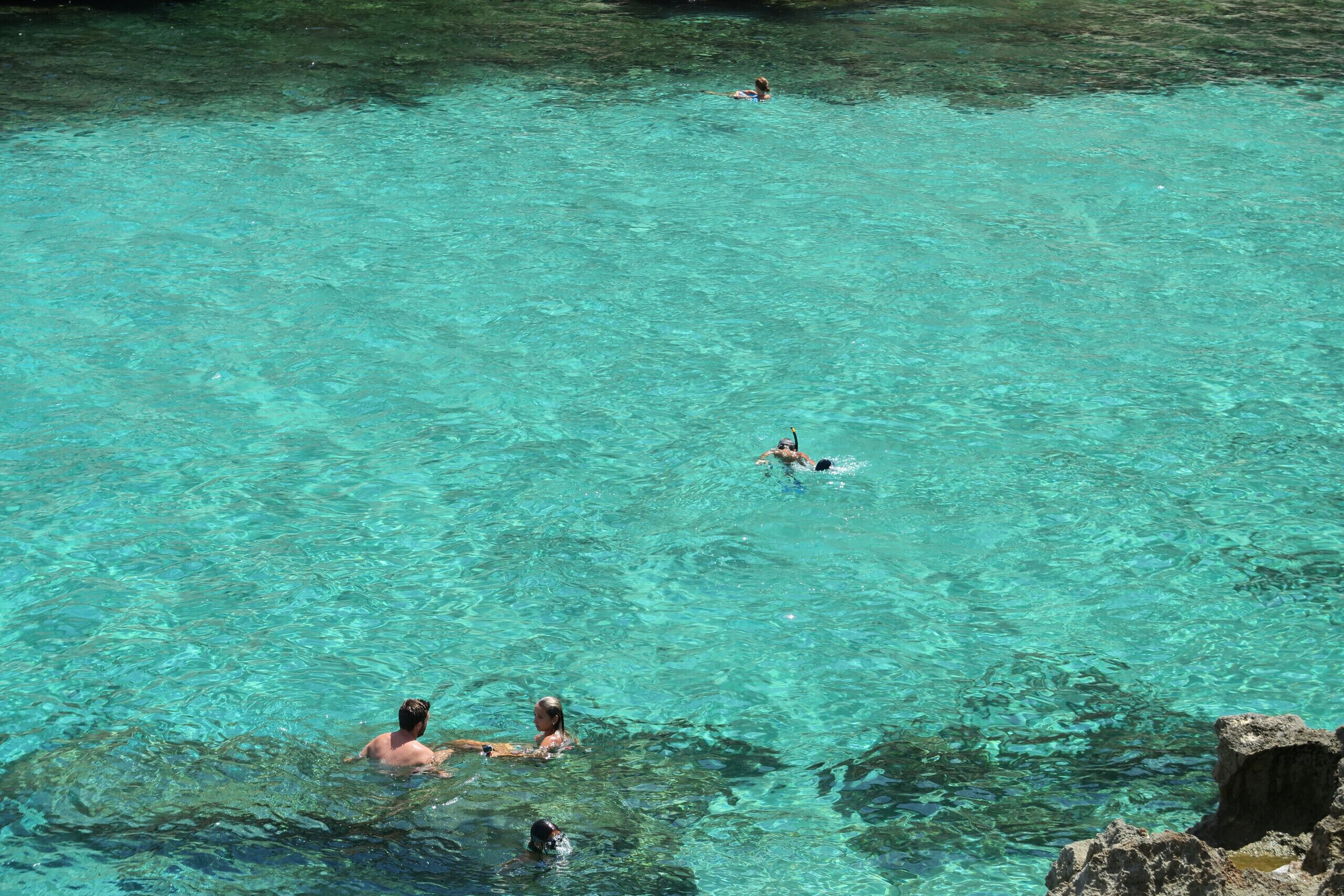 A clear turquoise pool surrounded by rocky terrain.