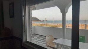 Ein Zimmer mit Blick auf Strand und Meer durch ein großes Fenster.