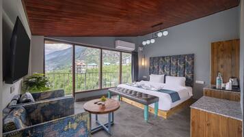 A bedroom with a bed, a sofa, a table, and a TV.