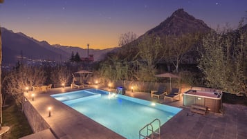Una piscina al aire libre, sombrillas, sillones reclinables de piscina