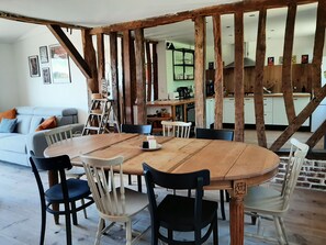 Un coin repas avec une table et des chaises en bois, un canapé et, au fond, une cuisine.