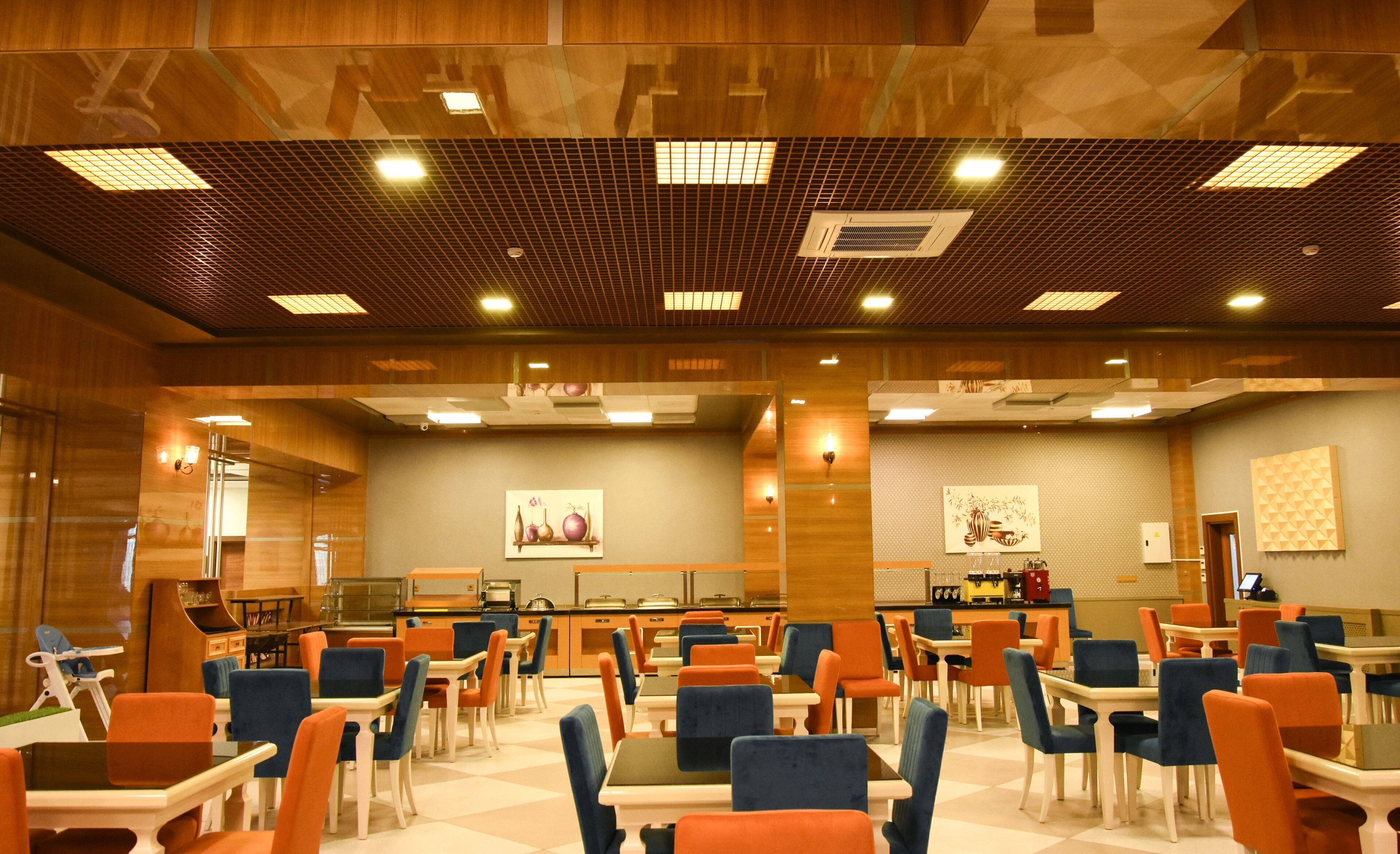 A hotel lobby with a check-in counter, seating area, and a kitchen in the background.