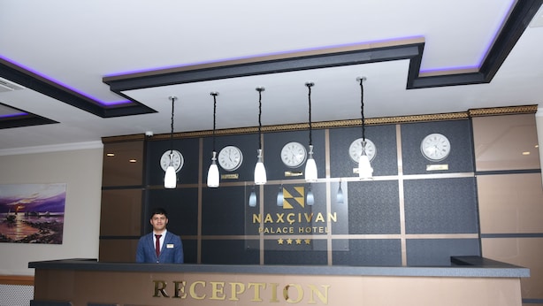 A reception desk with a nameplate for Naxçivan Palace Hotel, a clock, and a name tag holder. - Naxçıvan Palace Hotel (Nakhchivan)