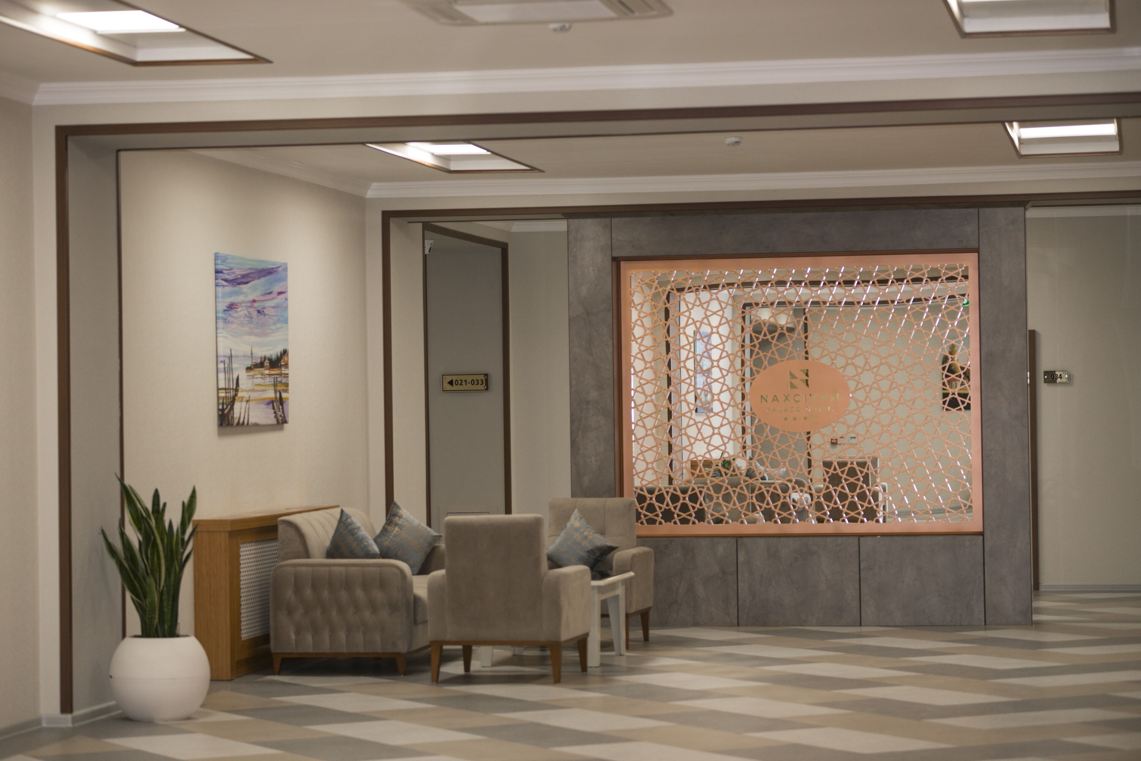 A modern lobby with a seating area, a decorative screen, and a framed artwork on the wall.