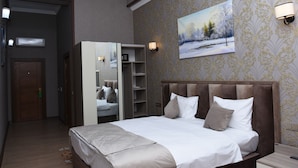A bedroom with a large bed, a wardrobe, a mirror, and a painting on the wall. - Naxçıvan Palace Hotel (Nakhchivan)