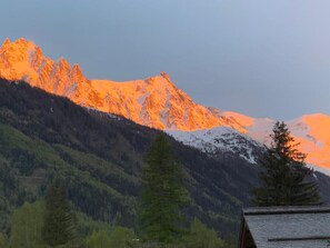 A mountain range with a cabin in the foreground.