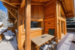 A wooden cabin with a wooden table and chairs, a window, and a door.