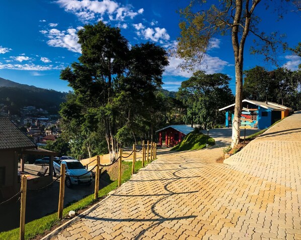 A paved pathway leading uphill with a view of a town and mountains in the background. - Chalés Vista Linda (Santo Antonio do Pinhal)