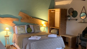 A cozy bedroom with a large bed, a brick fireplace, and a wooden ceiling. - Chalés Vista Linda (Santo Antonio do Pinhal)