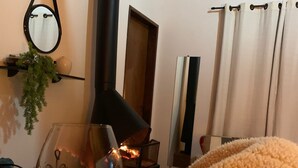 A cozy room with a fireplace, a mirror, and a window with curtains. - Chalés Vista Linda (Santo Antonio do Pinhal)