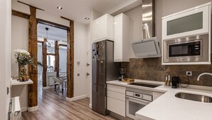 Una cocina moderna con armarios blancos, electrodomésticos de acero inoxidable y suelo de madera.