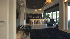 A modern living room with a black rug, a bar area with stools, and a large window providing a view of the outdoors. -  M House Art Hotel (Cervia)