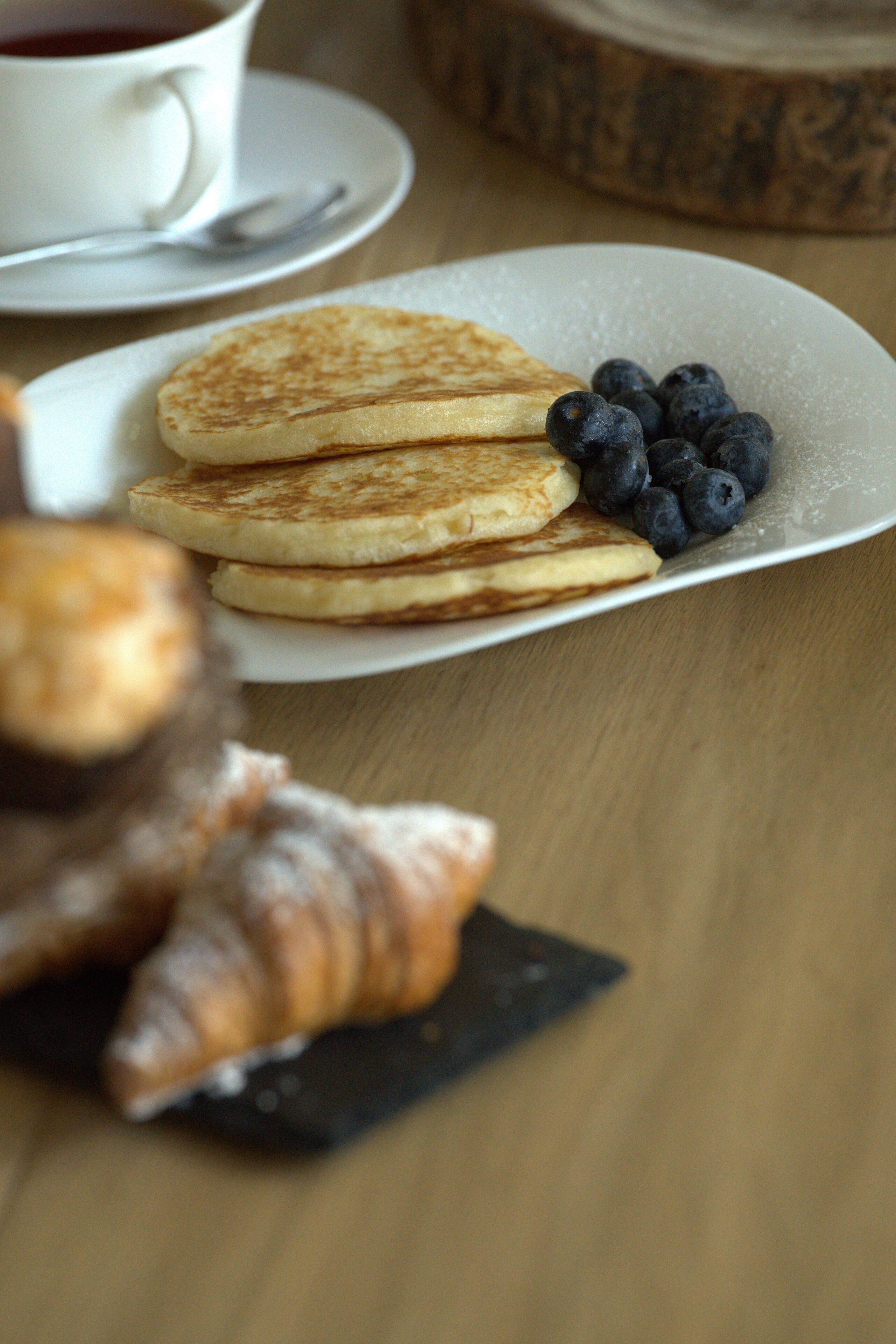 A plate with pancakes and blueberries on a wooden table.