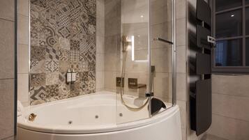 A modern bathroom with a freestanding bathtub, a glass shower enclosure, and a patterned tile backsplash.