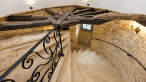 Eine Wendeltreppe mit Steinwänden und Holzbalken, mit einem schmiedeeisernen Geländer.