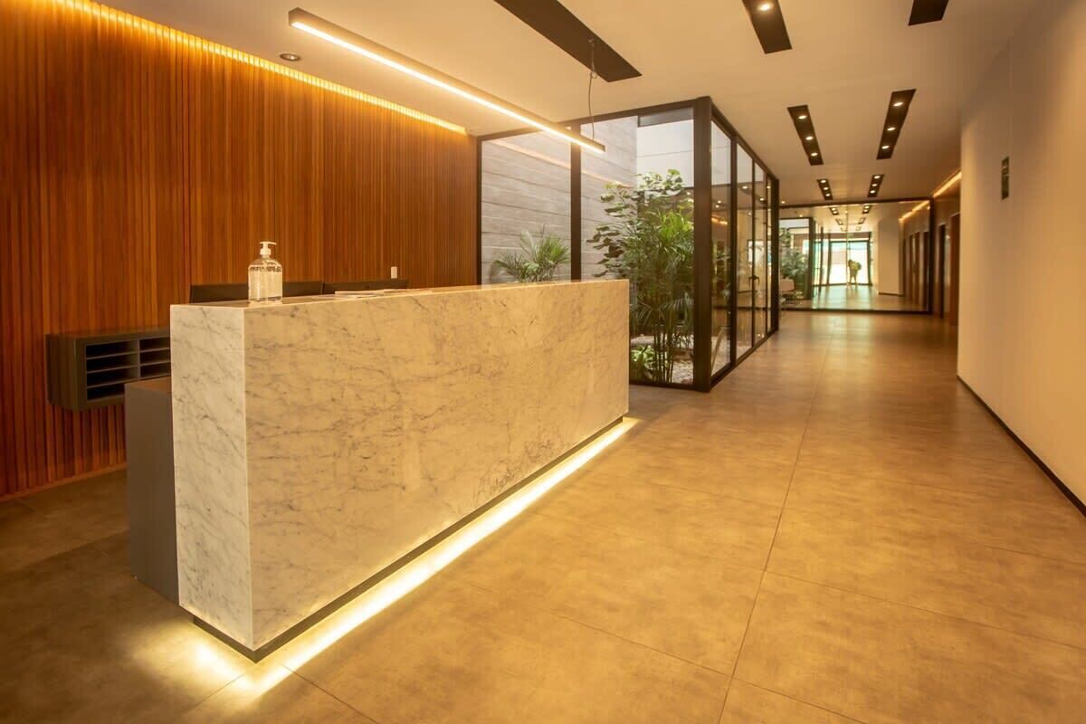 A modern reception area with a marble counter, wooden paneling, and a glass partition.