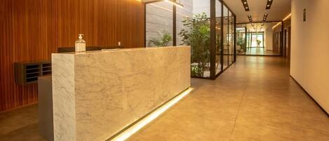 A modern reception area with a marble counter, wooden paneling, and a glass partition.