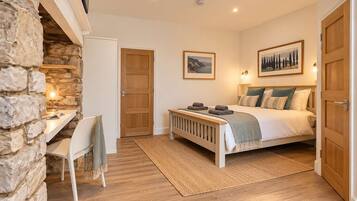 A bedroom with a bed, a desk, and a chair. There are two doors, one leading to the bathroom and the other to the bedroom.