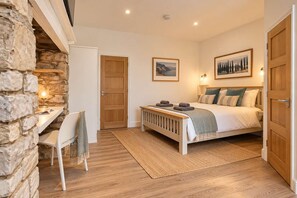 A bedroom with a bed, a desk, and a chair. There are two doors, one leading to the bathroom and the other to the bedroom.