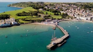 An aerial view of a coastal town with a marina, green hills, and residential buildings. - Dizzy Lows Sea View Apartment Swanage Town & Beach (Swanage)