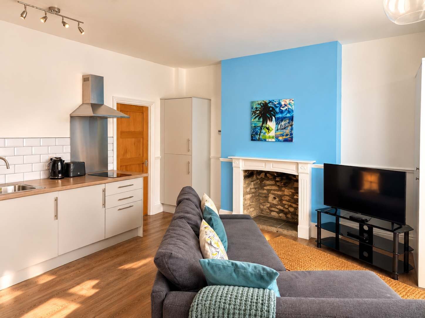 Ein modernes Wohnzimmer mit einem grauen Sofa, einem Kamin und einem Flachbildfernseher.