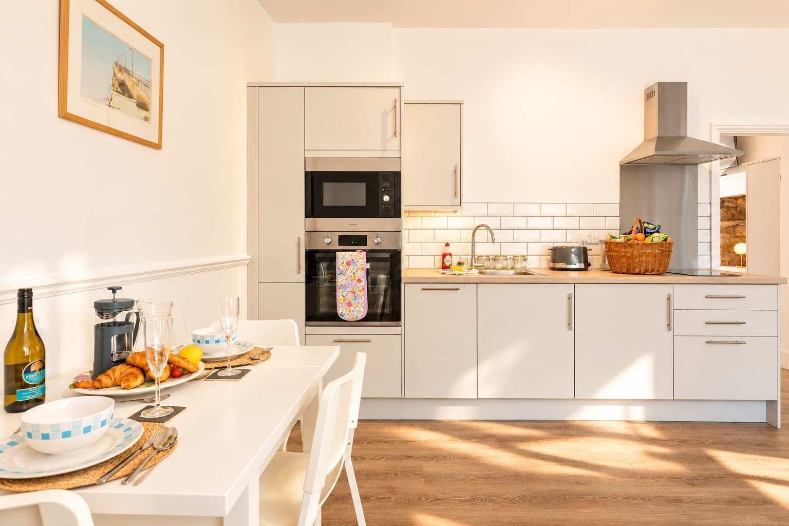 A modern kitchen with white cabinetry, a built-in oven, and a stainless steel range hood.