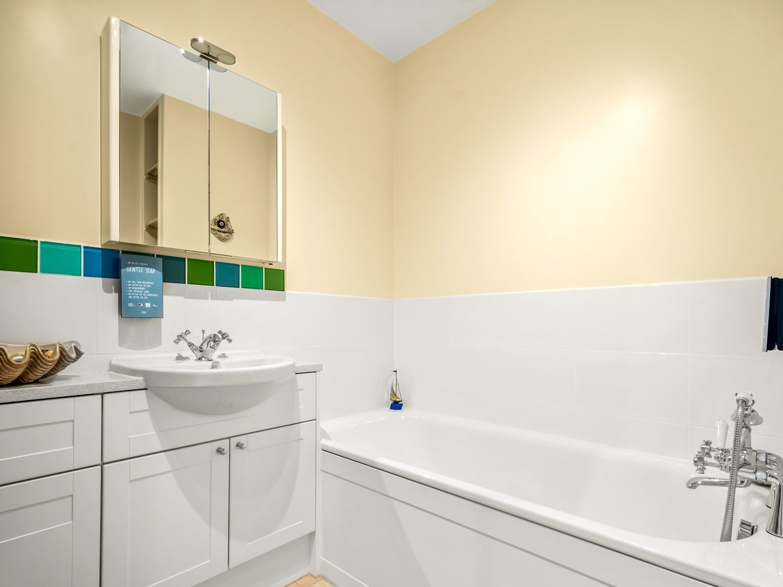 Un baño moderno con un lavamanos blanco, un espejo grande y una bañera.