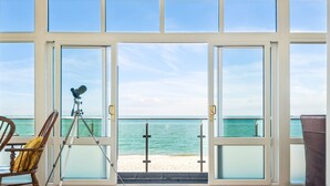A room with large windows overlooking a beach, a telescope, and a chair. - Jarrahdale Beach House - Stunning Luxurious Pad by the Beach - Pass the Keys (Herne Bay)