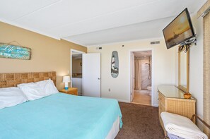 Une chambre d’hôtel comprenant un lit, une télévision, une salle de bain avec douche et une porte donnant sur une autre pièce.
