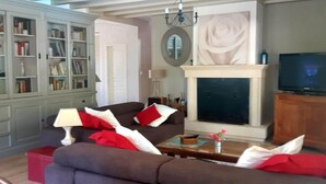 Ein Wohnzimmer mit einer Couch, einem Couchtisch, einem Fernseher, einem Kamin und einem Bücherregal.