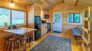 A wooden cabin interior with a kitchen, dining area, and seating space.