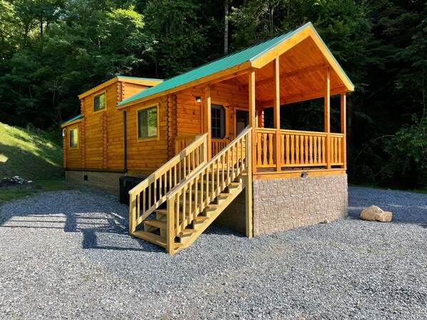 A two-story log cabin with a stone foundation, a wooden porch, and a staircase leading to the upper level. - Dogwood Cabin Unit 4-Wifi - Fire Pit - Mountain View & Stream (Bryson City)