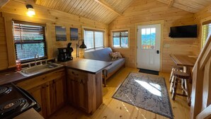 A cozy cabin interior with a kitchen, dining area, and a sofa. - Dogwood Cabin Unit 4-Wifi - Fire Pit - Mountain View & Stream (Bryson City)