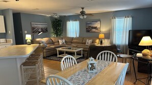 Una sala de estar moderna con comedor, cocina y televisor.