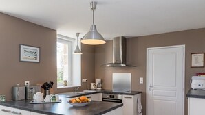 Una cocina moderna con una isla central, electrodomésticos de acero inoxidable e iluminación colgante.